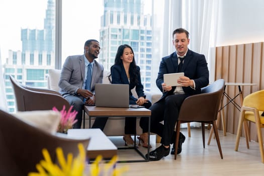 Smart caucasian businessman present marketing idea by using tablet. Group of business team listening while deciding to invest in start up project at modern lounge. Ornamented.