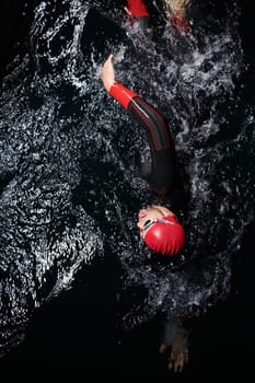 A determined professional triathlete undergoes rigorous night time training in cold waters, showcasing dedication and resilience in preparation for an upcoming triathlon swim competition.