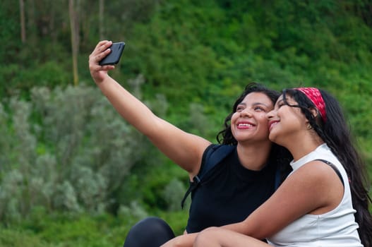 Two very smiling friends taking a selfie at the top of a mountain during a trip to Ecuador on their vacation. High quality photo