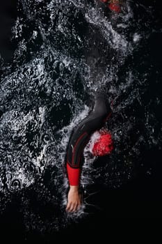 A determined professional triathlete undergoes rigorous night time training in cold waters, showcasing dedication and resilience in preparation for an upcoming triathlon swim competition.