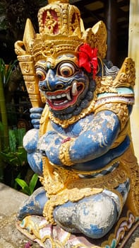 figure guarding the entrance to a Hindu temple, statue of sacred temple in Bali, balinese temple guardian, balinese gnome, Traditional Balinese statues or called Arca made of stone carvings in the form of gods, people or demons. Balinese sculpture in temple.