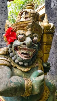figure guarding the entrance to a Hindu temple, statue of sacred temple in Bali, balinese temple guardian, balinese gnome, Traditional Balinese statues or called Arca made of stone carvings in the form of gods, people or demons. Balinese sculpture in temple.