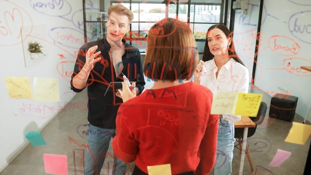 Creative start up team brainstorming marketing idea while cooperative caucasian businesswoman presents creative solution in front of glass board at business meeting. Working together. Immaculate.