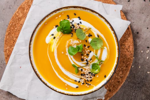 Delicious homemade creamy pumpkin soup with cream with sesame seeds and watercress.