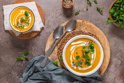 Delicious homemade creamy pumpkin soup with cream with sesame seeds and watercress.