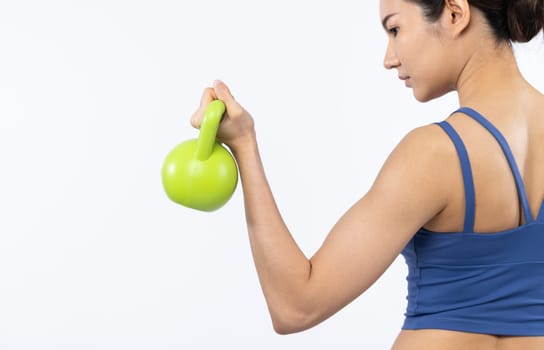 Vigorous energetic woman doing kettlebell weight lifting exercise on isolated background. Young athletic asian woman strength and endurance training session as body workout routine.