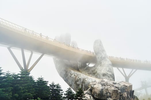 Danang, Vietnam - June 27, 2023: The Golden Bridge is lifted by two giant hands in the tourist resort on Ba Na Hill in Danang, Vietnam.