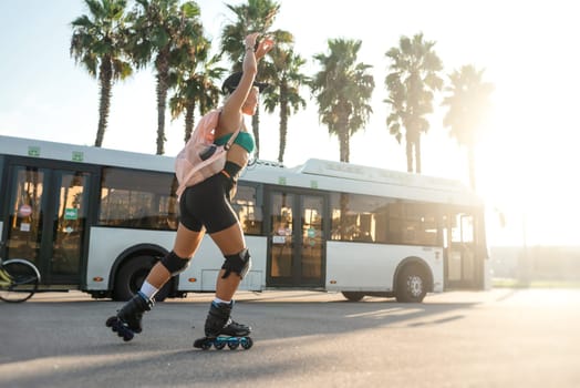 sporty girl on roller skates against the background of the city in the sunset light on a summer day