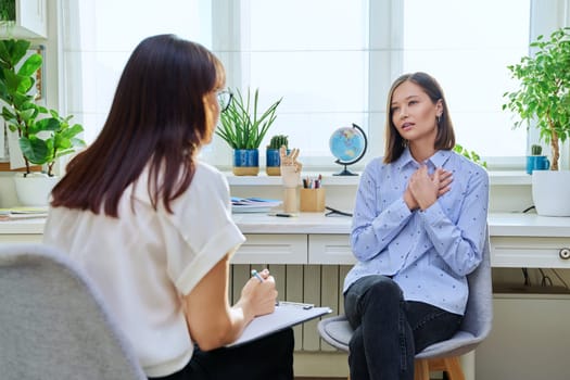 Sad stressed young woman in therapy with professional psychologist. Women talking in office, therapist counselor psychotherapist working with patient. Support, mental health, psychology, psychotherapy
