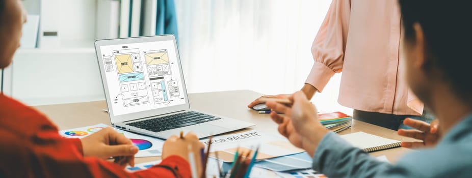 Cropped image of interior designer team discuss the material color while laptop displayed website wireframe designs for mobiles app and website. Creative design and business concept. Variegated.