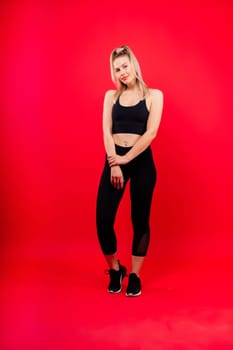 Beautiful young woman dressed in sports uniform, posing in studio on yellow red dark background.