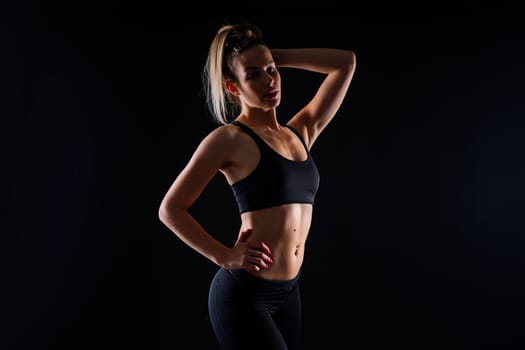 Beautiful young woman dressed in sports uniform, posing in studio on yellow red dark background.