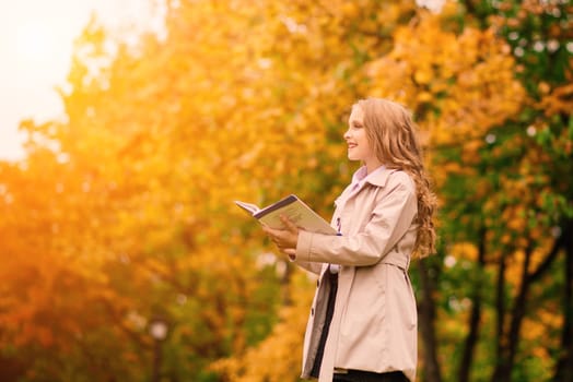 Portrait of a cute schoolgirl with interesting book in natural environment