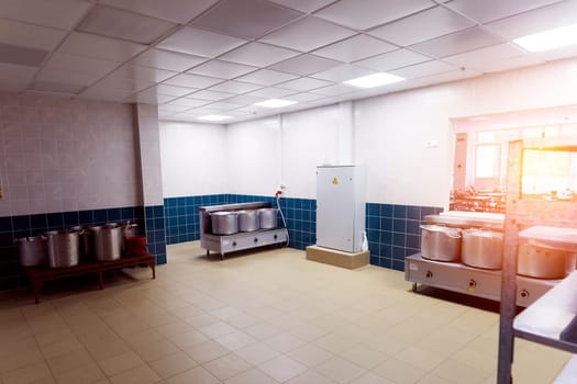 Industrial kitchen in school restaurant with professional equipment and pans