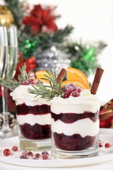 Christmas cranberry dessert tiramisu with mascarpone and whipped cream, chocolate biscuit crumble and cranberry jam, garnished with orange slices, candied cranberries and rosemary.