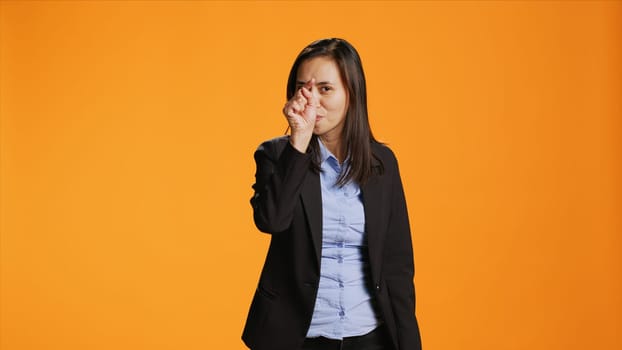 Asian office employee pointing fingers at camera, being serious and confident over orange background. Woman in formal clothes indicates something in front of her, point at the lens.