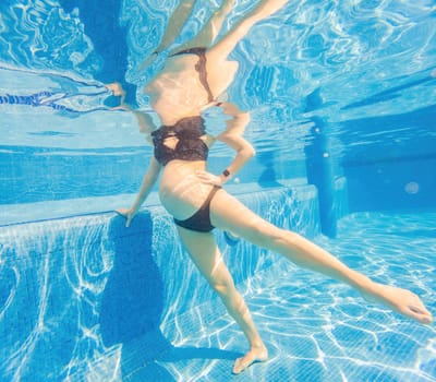 Embracing aquatic fitness, a pregnant woman demonstrates strength and serenity in underwater aerobics, creating a serene and empowering image in the pool.