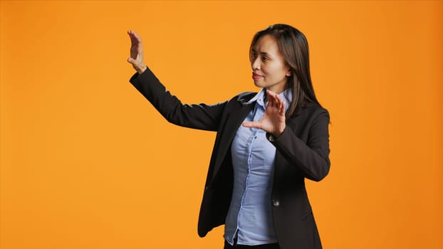 Office worker uses metaverse holographic image in studio, examining modern artificial intelligence reflection in front of camera. Businesswoman checks hologram icon projection.