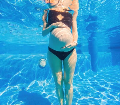 Pregnancy embraced underwater a tranquil scene as a woman tenderly hugs her belly in the pool, capturing the beauty of maternal connection.