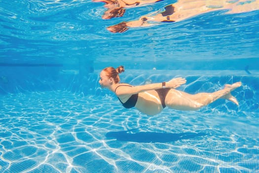 Pregnant serenity submerged a woman gracefully dives into the pool, celebrating the beauty of pregnancy with aquatic elegance.