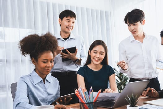 Multiracial analyst team use BI dashboard data to analyze financial report on meeting table. Group of diverse business people utilize data analysis by FIntech for success business marketing. Concord