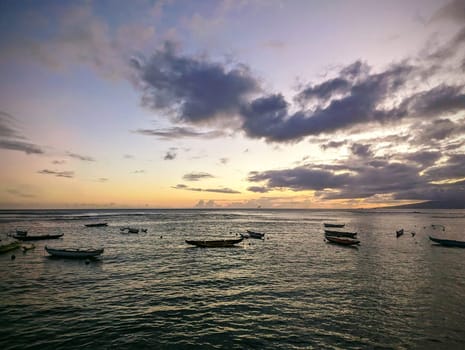 Dusk over the ocean reflecting on the water with boats park in ocean on Oahu, Hawaii.