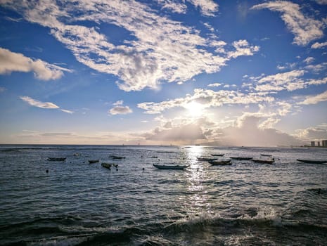 Sunset over the ocean reflecting on the water with boats park in ocean on Oahu, Hawaii.