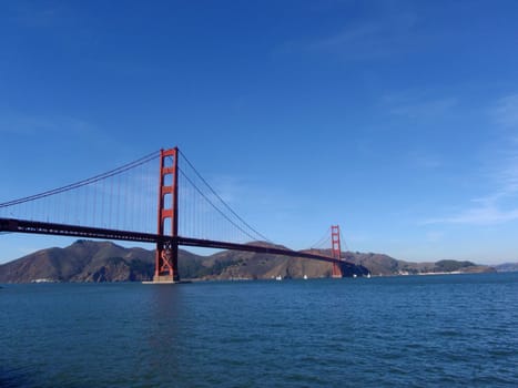 The iconic Golden Gate Bridge in San Francisco, California on a clear day with blue skies and calm waters.