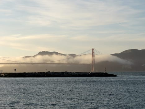 A stunning view of the Golden Gate Bridge in San Francisco, California, partially covered by fog on a clear day     