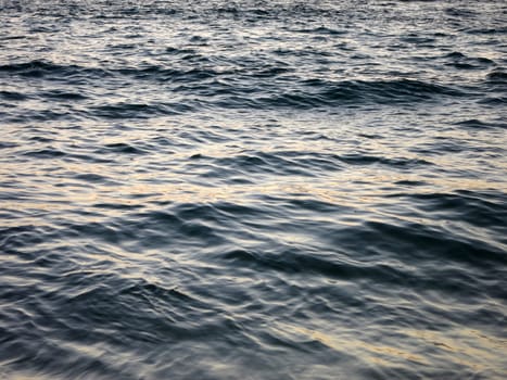 Ocean water off Waikiki, Hawaii, with a rippled texture and a warm glow from the setting sun.                     