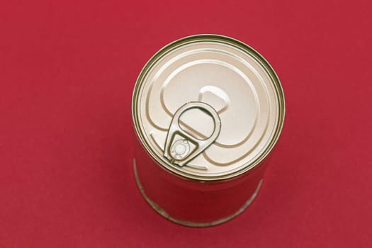 Unopened Tin Can with Blank Edge on Red Background. Canned Food. Aluminum Can for Safe and Long Term Storage of Food. Steel Sealed Food Storage Container