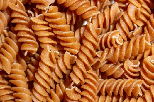 Uncooked Whole Grain Fusilli Pasta: A Culinary Canvas of Whole Wheat Spirals, Creating a Lively and Textured Background for Gourmet Cooking. Whole Grain Twisted Dry Pasta. Whole Wheat Raw Macaroni