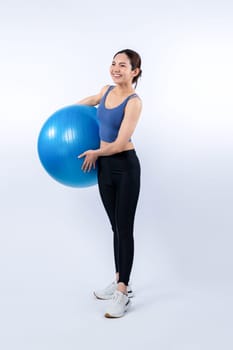 Young attractive asian woman portrait in sportswear with fit ball targeting on abs muscle for effective energetic daily workout routine. Studio shot and isolated background. Vigorous