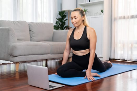 Senior woman in sportswear being doing yoga in meditation posture on exercising mat at home. Healthy senior pensioner lifestyle with peaceful mind and serenity. Clout