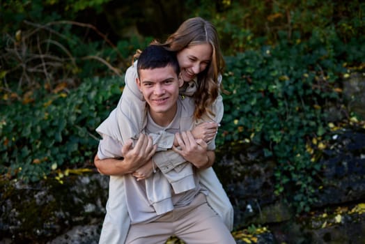 Young Cute Female Hugs Boyfriend. In Autumn Outdoor. Lovers Walking in Park. Attractive Funny Couple. Lovestory in Forest. Man and Woman. Cute Lovers in the Park. Family Concept. Happy Couple.