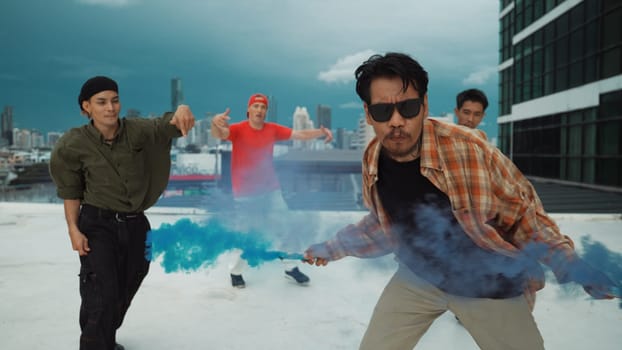 Group of multicultural hipster playing color flare at rooftop. Attractive street dancer holding colored smoke and perform break dance move to hip-hop music. Outdoor sport 2024. Endeavor.