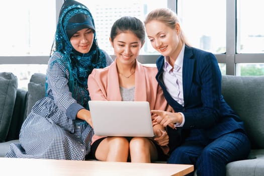 Multicultural working group. Team of businesswomen of different ethnicity, Caucasian, Asian and Arabic working together with laptop computer at office workplace. Multiethnic teamwork concept. uds