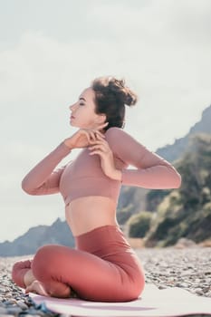 Young woman with long hair in white swimsuit and boho style braclets practicing outdoors on yoga mat by the sea on a sunset. Women's yoga fitness routine. Healthy lifestyle, harmony and meditation