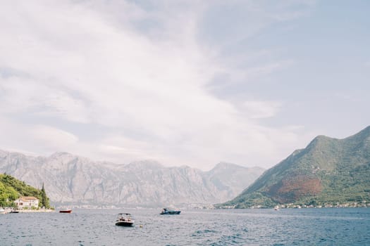 Motorboats sail along the Bay of Kotor against the backdrop of green mountains. Montenegro. High quality photo