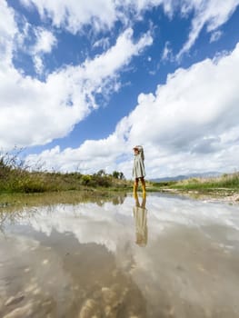 Little girl stands in a puddle with her hand visor to her forehead. High quality photo