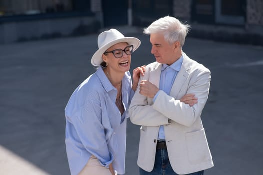 Stylish elderly laughing couple on a walk. Romantic relationships of mature people