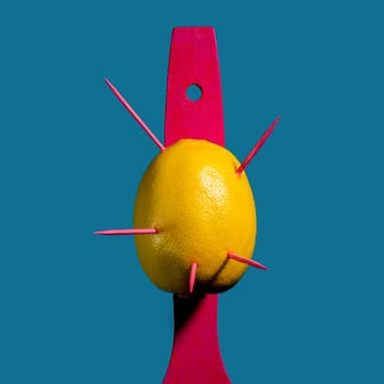 Creative still life with lemon struck by arrows on a blue background