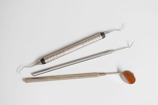 Dental mirror, explorer, hook, and dental tools on the white background.