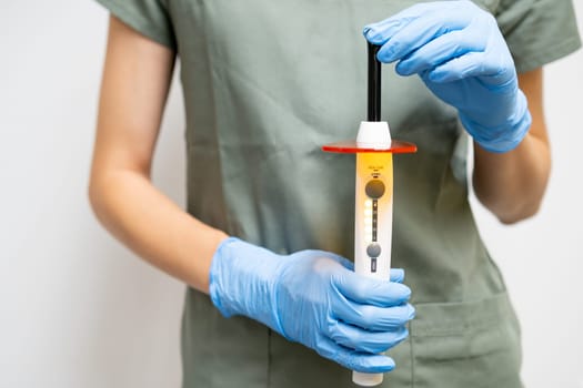 Dentist holding dental curing light in hands in rubber gloves