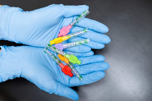 Interdental Toothbrushes in dentists hands in rubber gloves on the black background, December 2023, Prague, Czech Republic