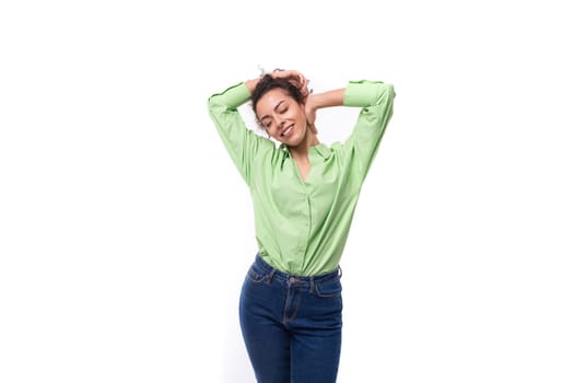 charming young brunette curly woman dressed in a green shirt and jeans.