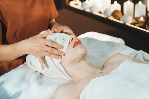 Portrait of beautiful caucasian woman having facial massage with homemade facial mask while lies on spa bed surrounded by beauty electrical equipment and peaceful nature environment. Tranquility.