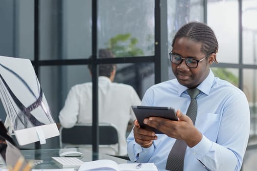 a man at a workplace at a table in front of a computer uses a tablet at office