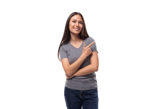 young well-groomed caucasian woman with dark straight hair is dressed in a casual gray t-shirt on a studio background with copy space.