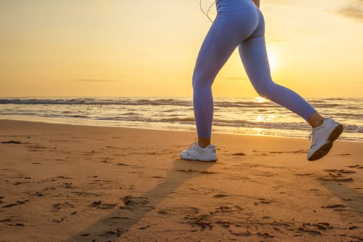 legs of a girl in blue leggings and sneakers running along the beach at dawn with space for inscription. High quality photo